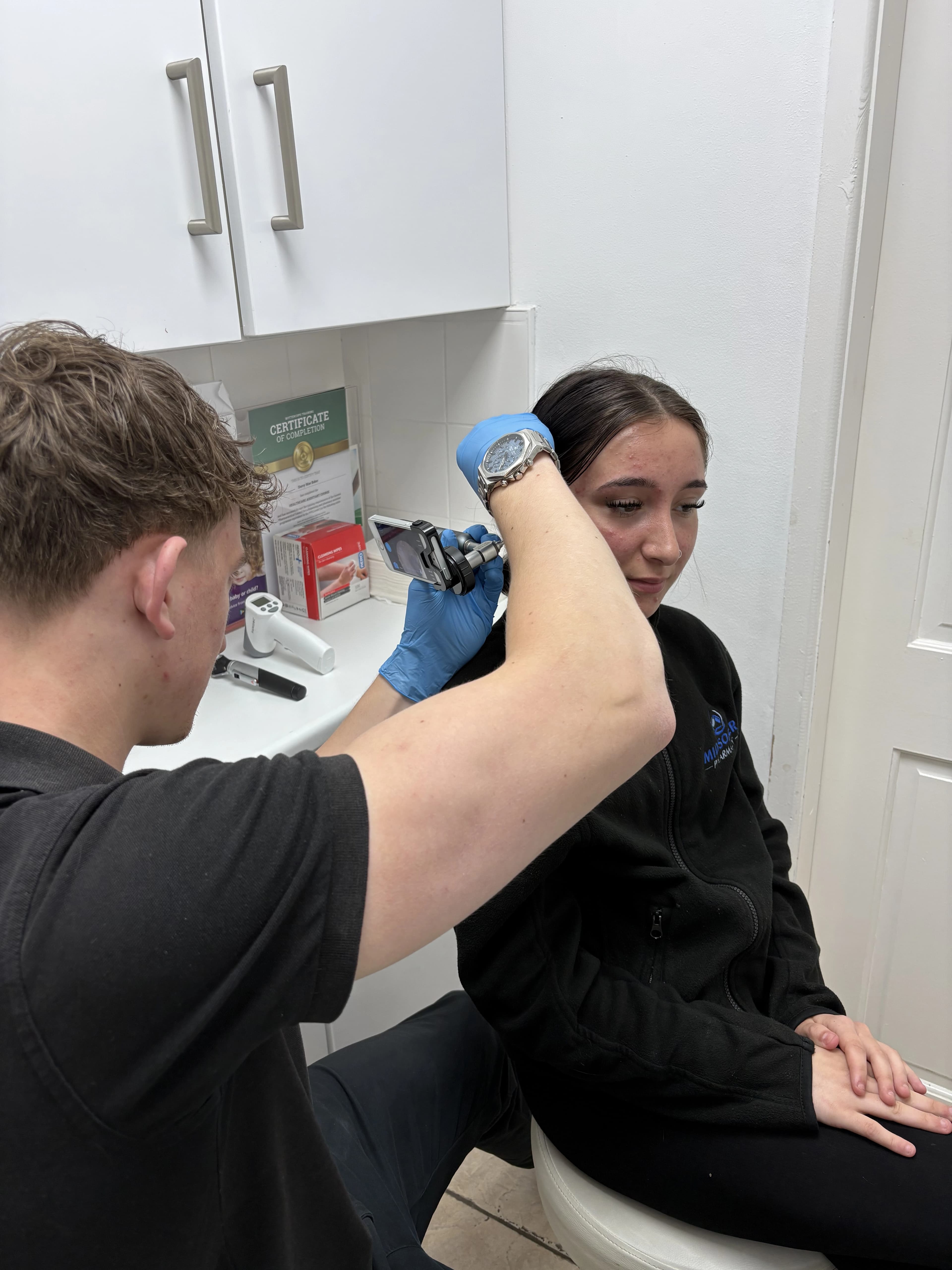 Pharmacist performing a microsuction earwax removal procedure